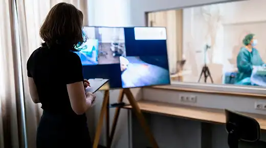 A woman seen from the back evaluates a testing situation in the Johner Institute usability laboratory.