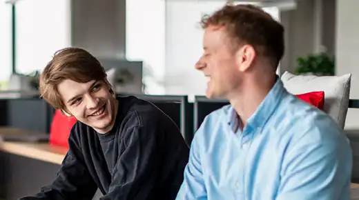 Two colleagues in the office are talking and laughing.