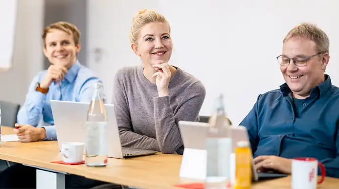 Three people in the office listen to a presentation