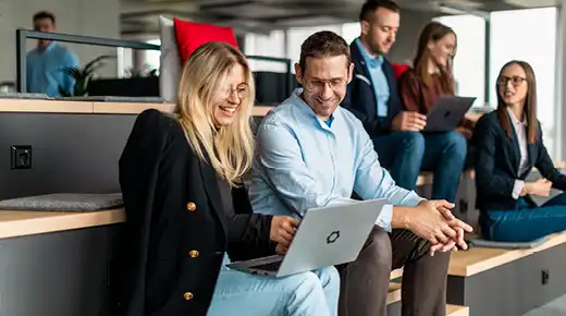 Colleagues in the office sit together at laptops
