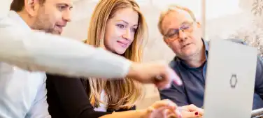 Three employees discussing something in front of a laptop