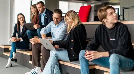 Two colleagues are looking at something on a laptop in the office.