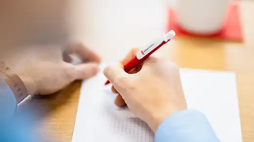 two hands taking notes with pen and paper