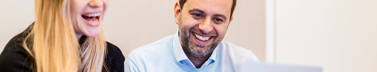 Two colleagues view something on a laptop