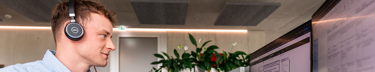 Man listens to something with his headset, sitting at his office desk