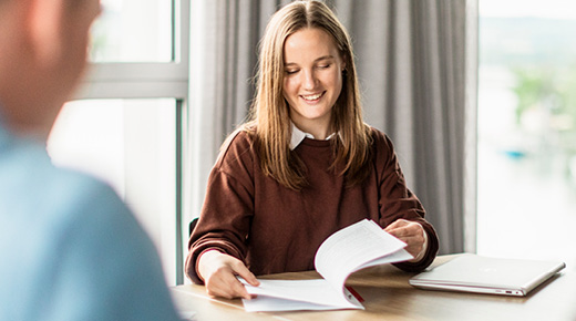 A woman reviewing a file on a desk in front of her