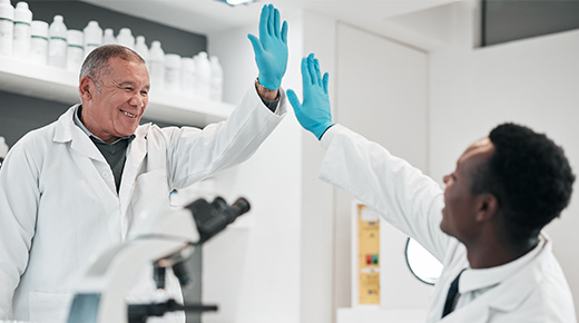 Two colleagues in a laboratory high-five each other