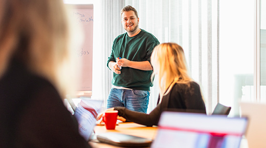 Men presenting something to a group in front of a whiteboard.