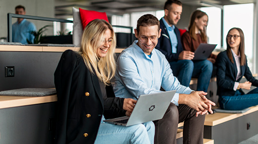 Two people in a co-working space view something on a laptop