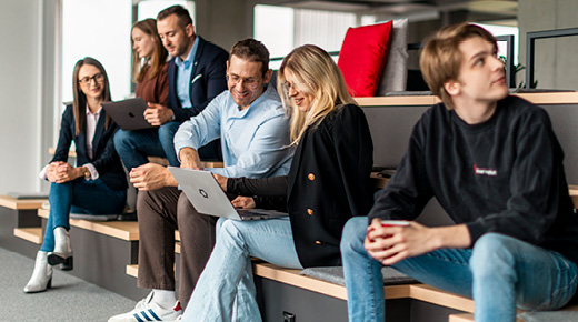Employees with laptops sit in a co-working space