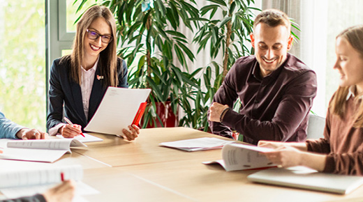 A team of three analyzes documents in a conference room.