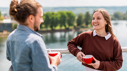 Two colleagues drink coffee on the roof top of the headquarters.